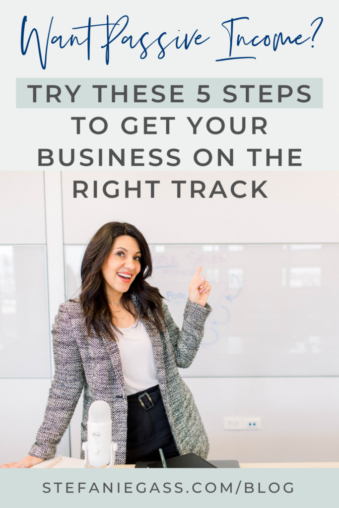 Brown haired woman standing at a desk with a white microphone in front of her. She is wearing a grey blazer, white blouse, and black pants. Her left arm is up, pointing to the title. The title is "Want Passive Income? Try These 5 Steps to Get Your Business on the Right Track" The link at the bottom is stefaniegass.com/blog