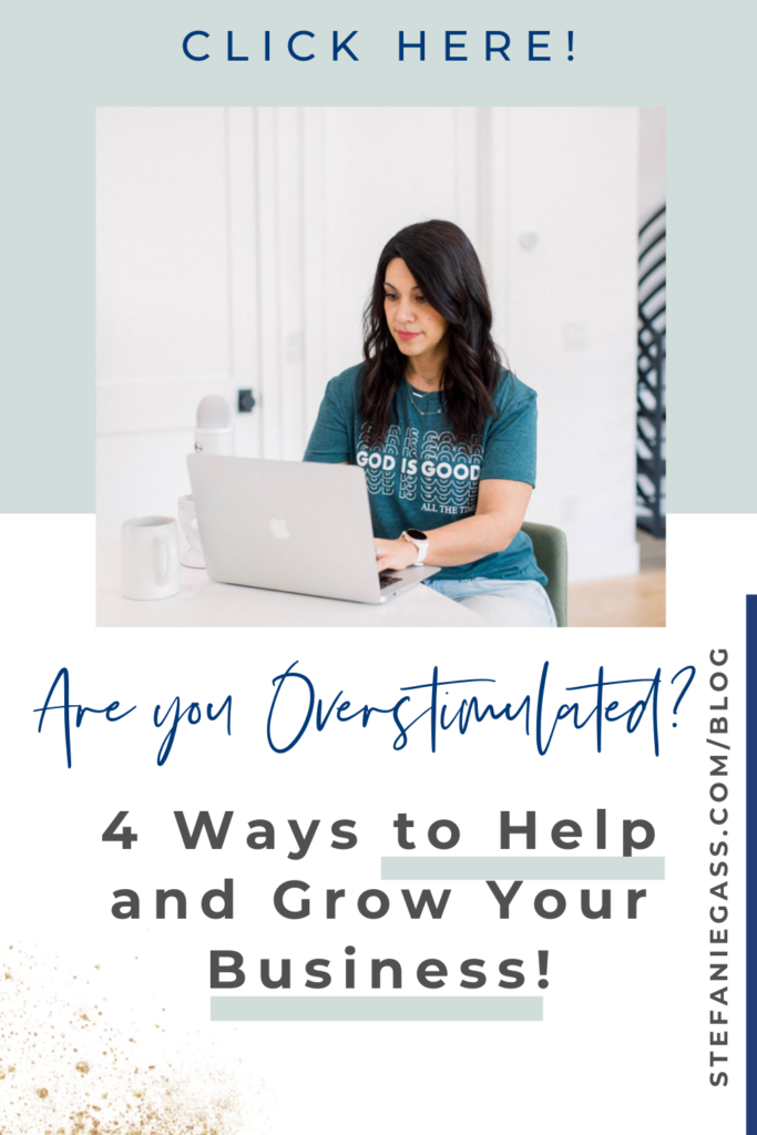 A long, dark-haired woman is sitting at a desk with her laptop open. She is typing and looking at the screen. She is wearing a blue graphic tee that says God is Good. There is a podcast mic to her side, with a cup of coffee also. The title of the graphic is Are you overstimulated? 4 ways to help and grow your business. The link on the right hand side of the graphic is stefaniegass.com/blog