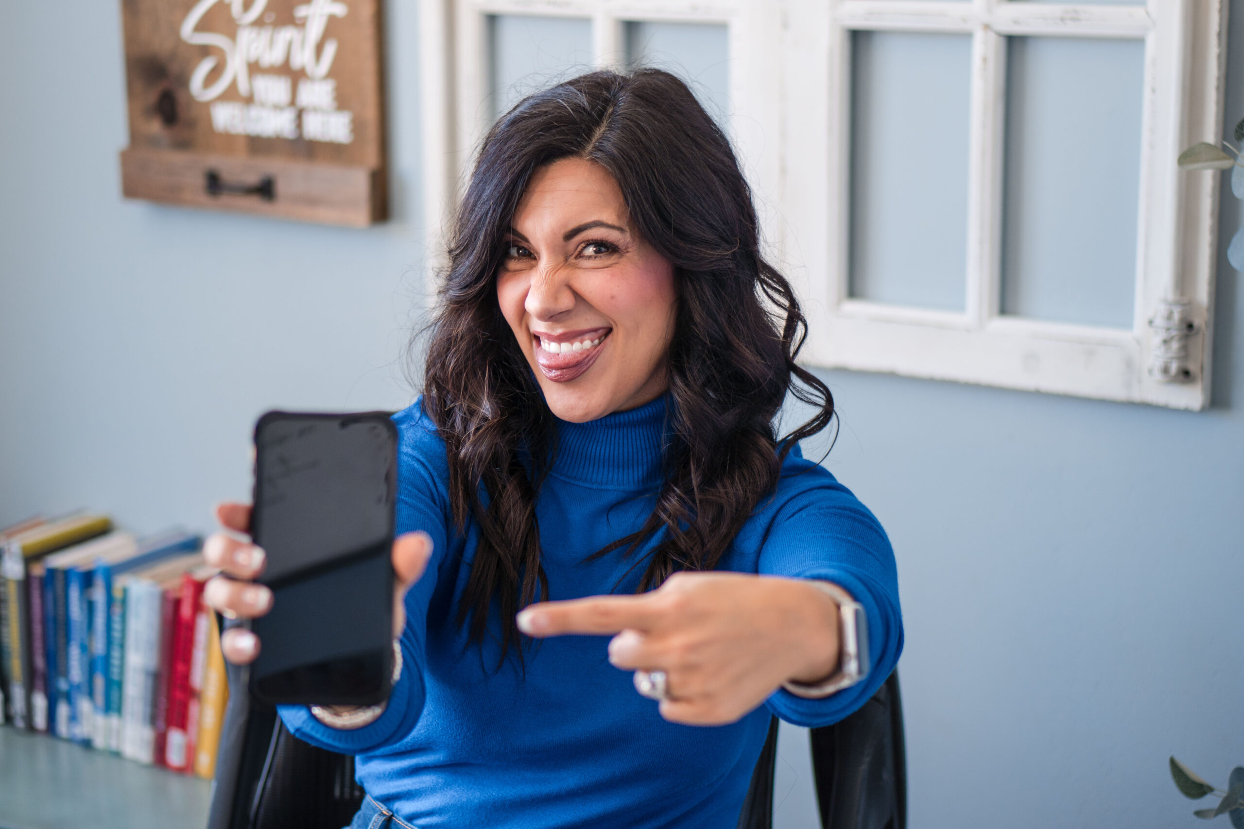 holding-phone-up-and-pointing-at-it-in-office-tounge-out-laughing-stefanie-gass The image title: Ep-837-Social-Media-Truth-Bombs-You-May-Not-Want-to-Know-Stefanie-Gass-Branded