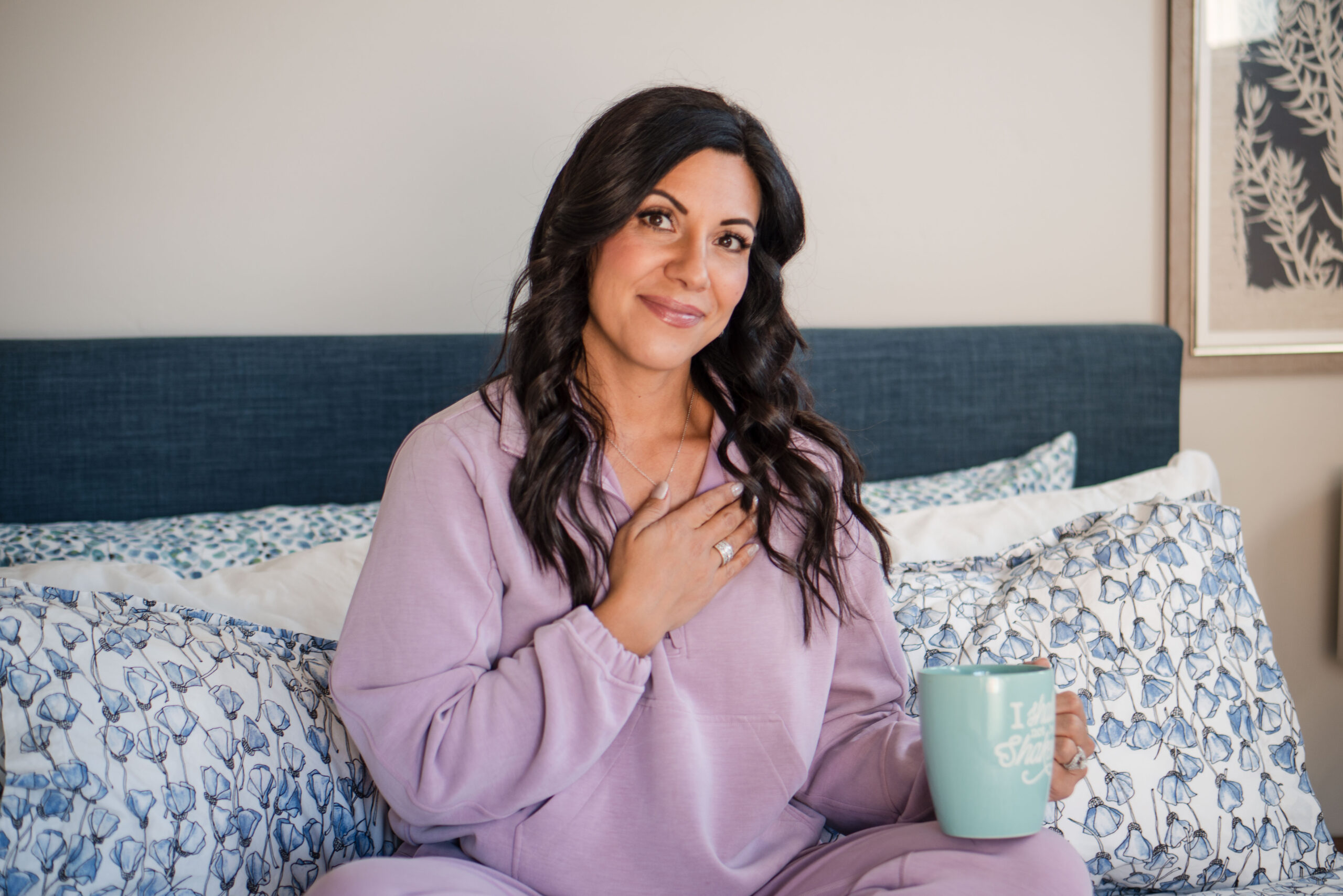 sitting-on-bed-holding-coffee-with-left-hand-right-hand-on-chest-smile-Stefanie-Gass-horizontal The image title is: Ep-716-My-Personal-Walk-With-God-Interview-With-Michelle-Onuorah-From-the-Prophetic-Listening-Podcast-Stefanie-Gass