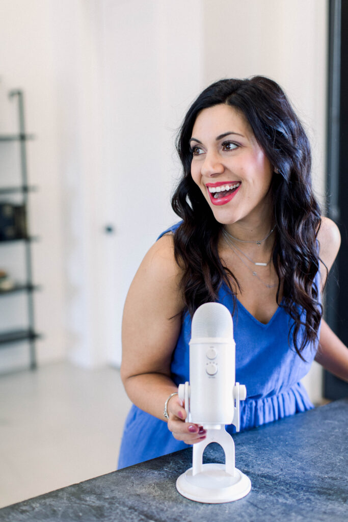 brown haired woman smiling with a podcast microphone in her hand  Blog is about sharing 17 lessons from My SECOND Speaking Engagement – Her Turn to Podcast with Cathy Heller  Stefanie Gass