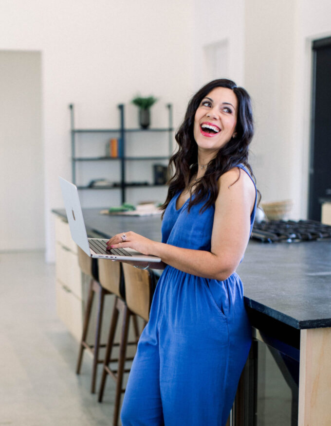Graphic is a picture of a dark haired woman in blue smiling while leaning against a countertop.