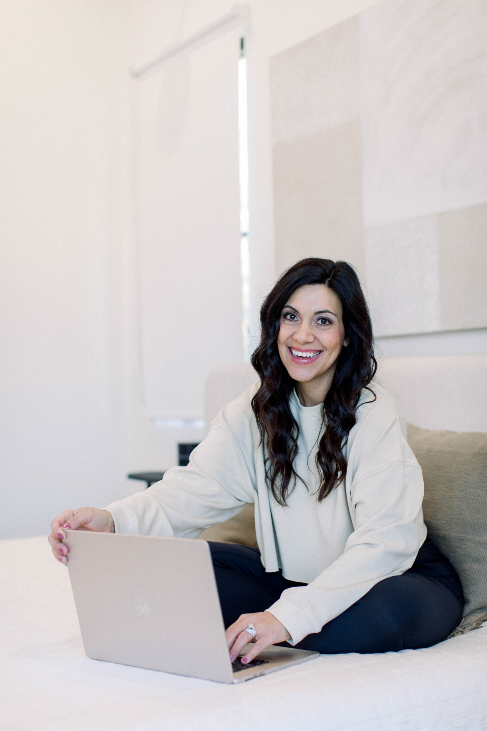 Dark haired woman smiling while holding open her computer.