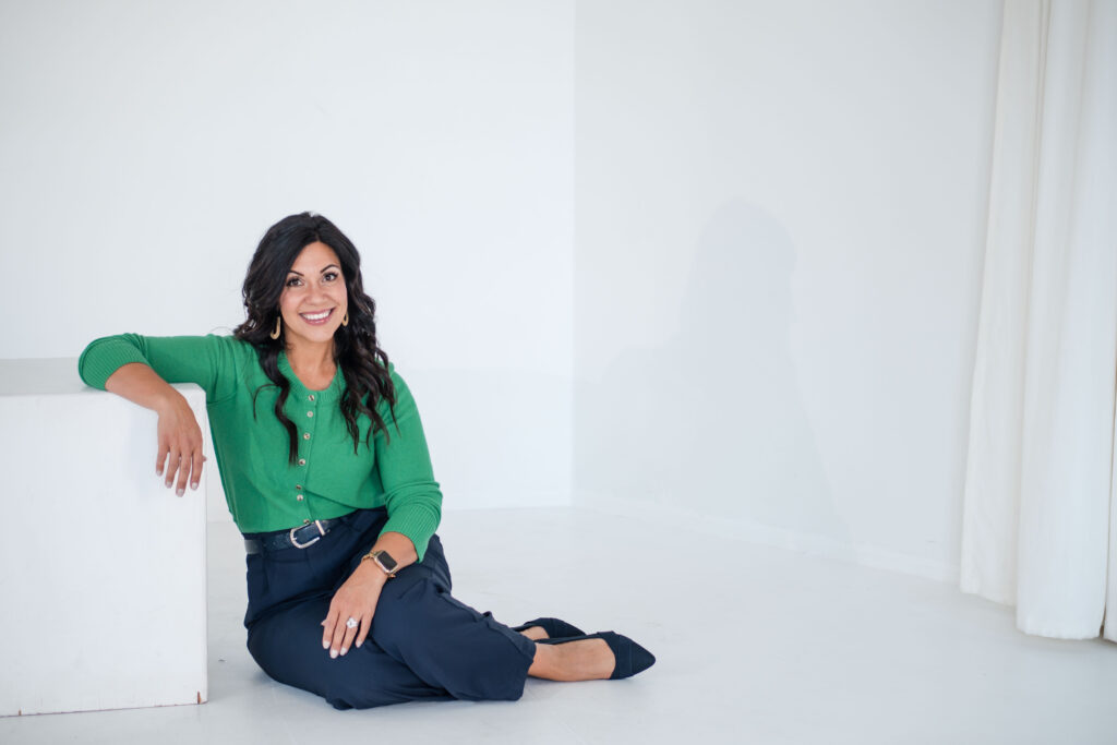 A brunette woman is lying on the floor with her arm over a white cube. She's wearing a green sweater, dark blue jeans, and black flats. The title of the image is: 788-Map-Out-an-Urgency-Offer-or-Challenge-That-Will-Increase-Sales-Stefanie-Gass