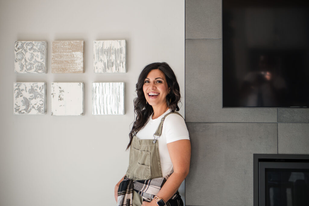 Brunette woman smiling while leaning against a wall. She's wearing green overalls and a white T-shirt. The image title is: How-to-Become-a-Full-Time-Podcaster-6-Steps-to-Monetize-So-You-Can-Quit-Your-Job-Stefanie-Gass