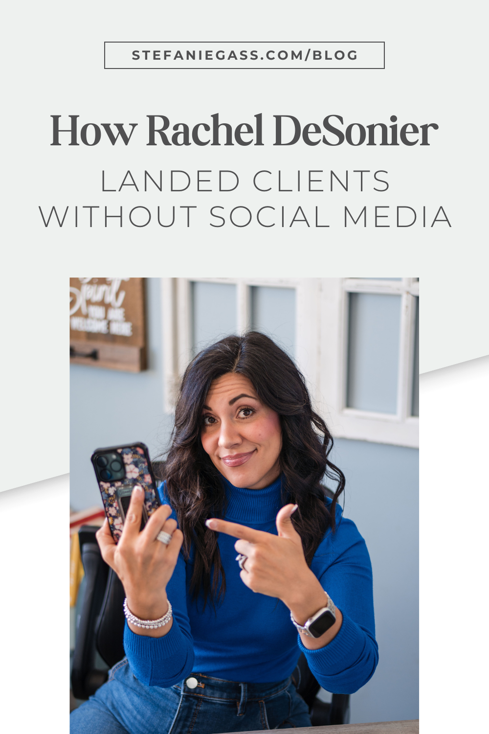 A graphic where Stefanie Gass, business and podcast coach, is wearing a bright blue sweater, a pair of blue jeans, a silver watch, some silver bracelets, and silver rings. She's holding her phone in one hand while pointing to it with the other hand. The image title is: Ep-832-How-Rachel-DeSonier-Landed-Clients-Without-Social-Media-Stefanie-Gass-Branded