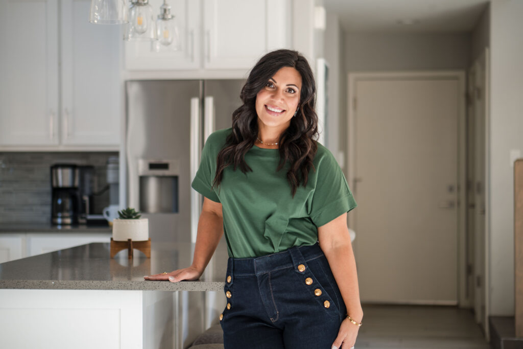 in-kitchen-hand-on-counter-leaning-back-happy-stefanie-gass-horizontal The image title is: Ep-827-How-She-Filled-Her-Group-Coaching-Program-and-Hit-130K-Podcast-Downloads-With-Lisa-Limehouse-Graphics-Stefanie-Gass