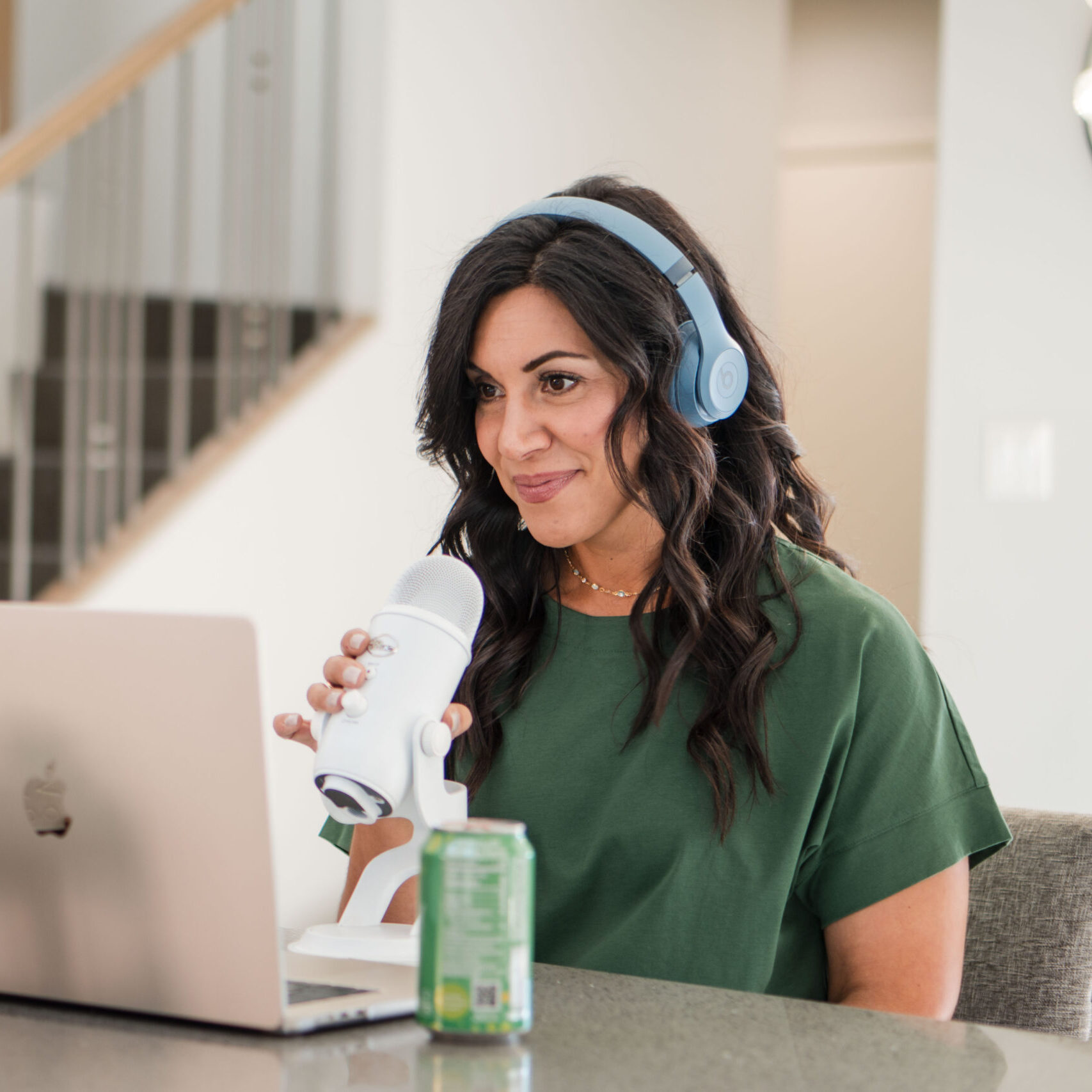 in-kitchen-holding-onto-microphone-calmly-looking-at-computer-stefanie-gass-horizontal The image title is: Ep-829-Podcasting-Basics-and-Tips-for-Business-Beginners-Stefanie-Gass