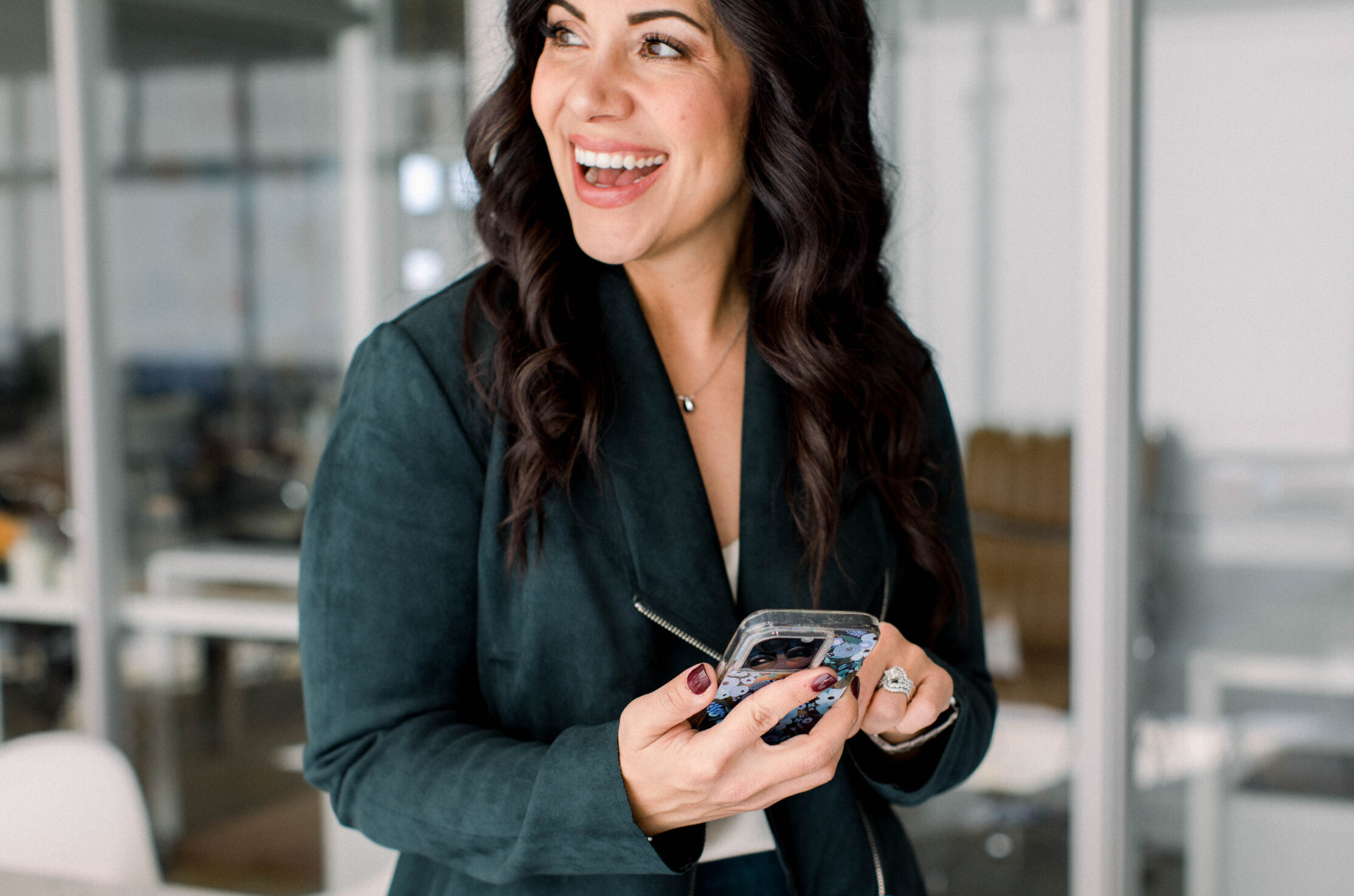 phone-in-hand-smiling-face-looking-away-from-camera-in-office-stefanie-gass The image title is: Ep-832-How-Rachel-DeSonier-Landed-Clients-Without-Social-Media-Stefanie-Gass